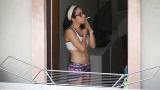 Brunette neighbor with glasses while smoking on the balcony