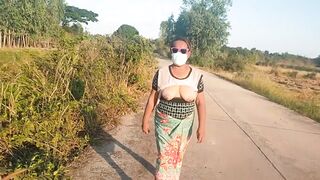 Auntie walks and shows off her breasts on the side of the road.